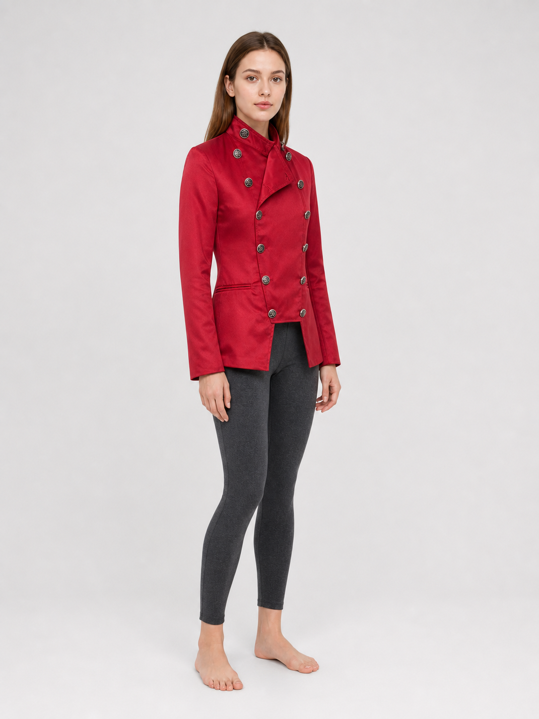 The jacket is presented in a vintage red color and designed in a military style with elements of Gothic aesthetics. The model features a distinctive front construction with a diagonal wrap, giving the garment a bold character. A double row 