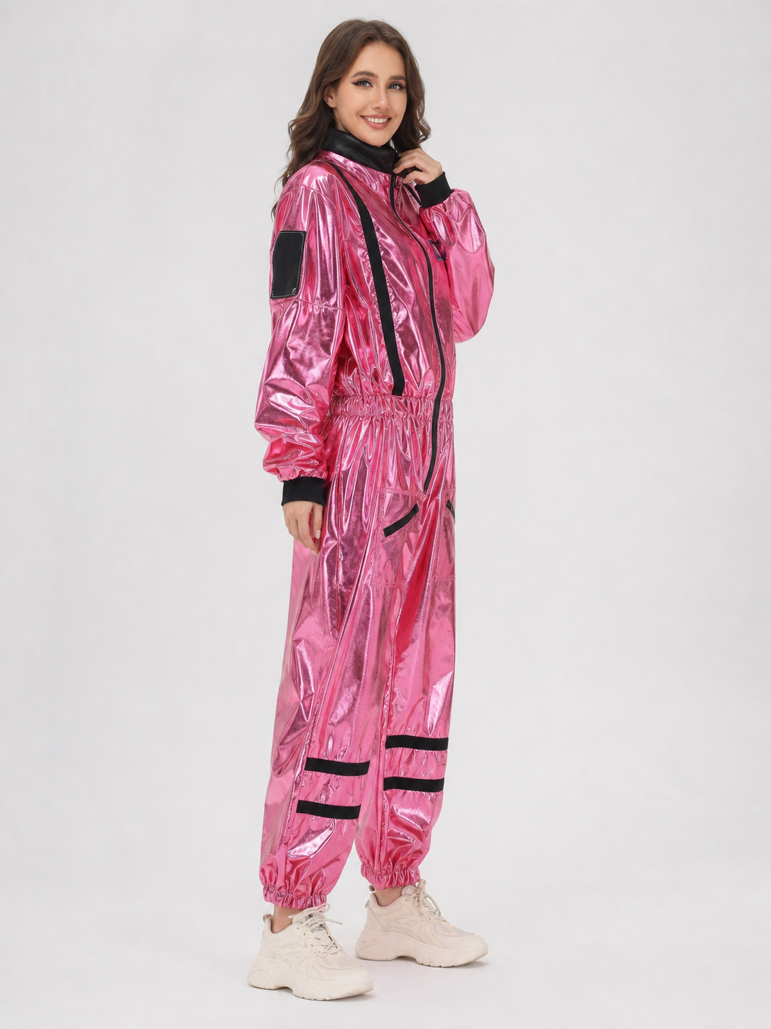 The pink NASA astronaut costume is designed as a one-piece jumpsuit with long sleeves, a stand-up collar, and a central zip closure. The model is pink with black decorative elements: a vertical stripe on the front, zippered side pockets, ho