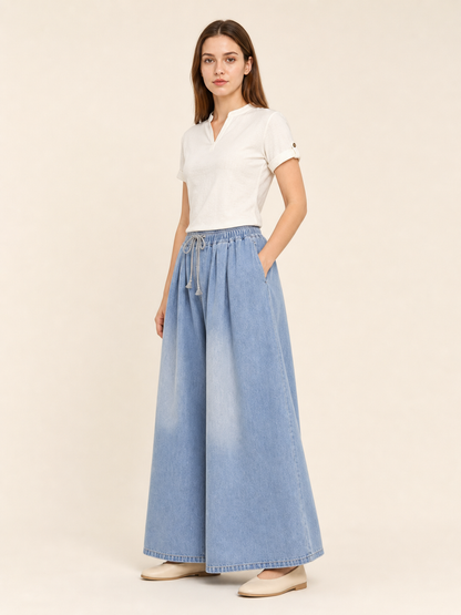 The model features a relaxed style with very wide, full-length legs that create a laid-back silhouette and suit everyday looks. The light blue shade with a subtle denim-like effect makes the piece versatile for warm weather and easy to pair