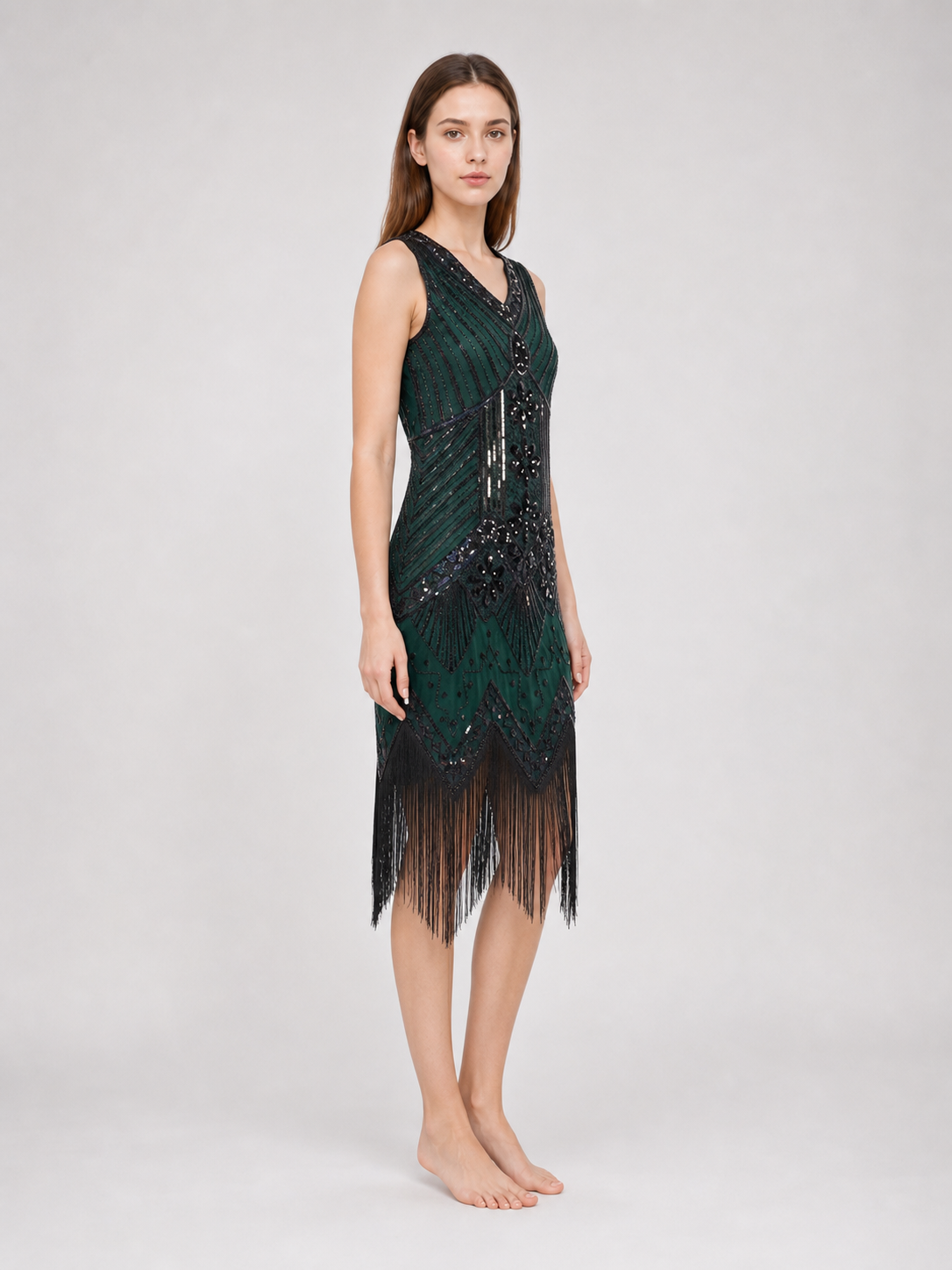 The flapper dress is designed in the Art Deco aesthetic and conveys the signature look of the Gatsby era. The sleeveless design features a V-neckline and a straight silhouette. A geometric and fan-shaped pattern covers the entire surface, c