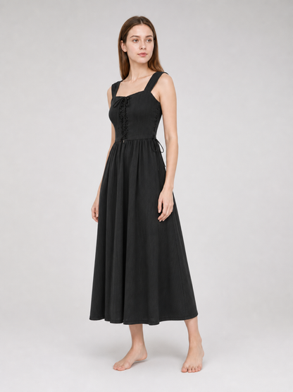 Three-quarter view of a black midi dress on a model, showing the lace-up front, wide shoulder straps, side ties, and flared midi skirt