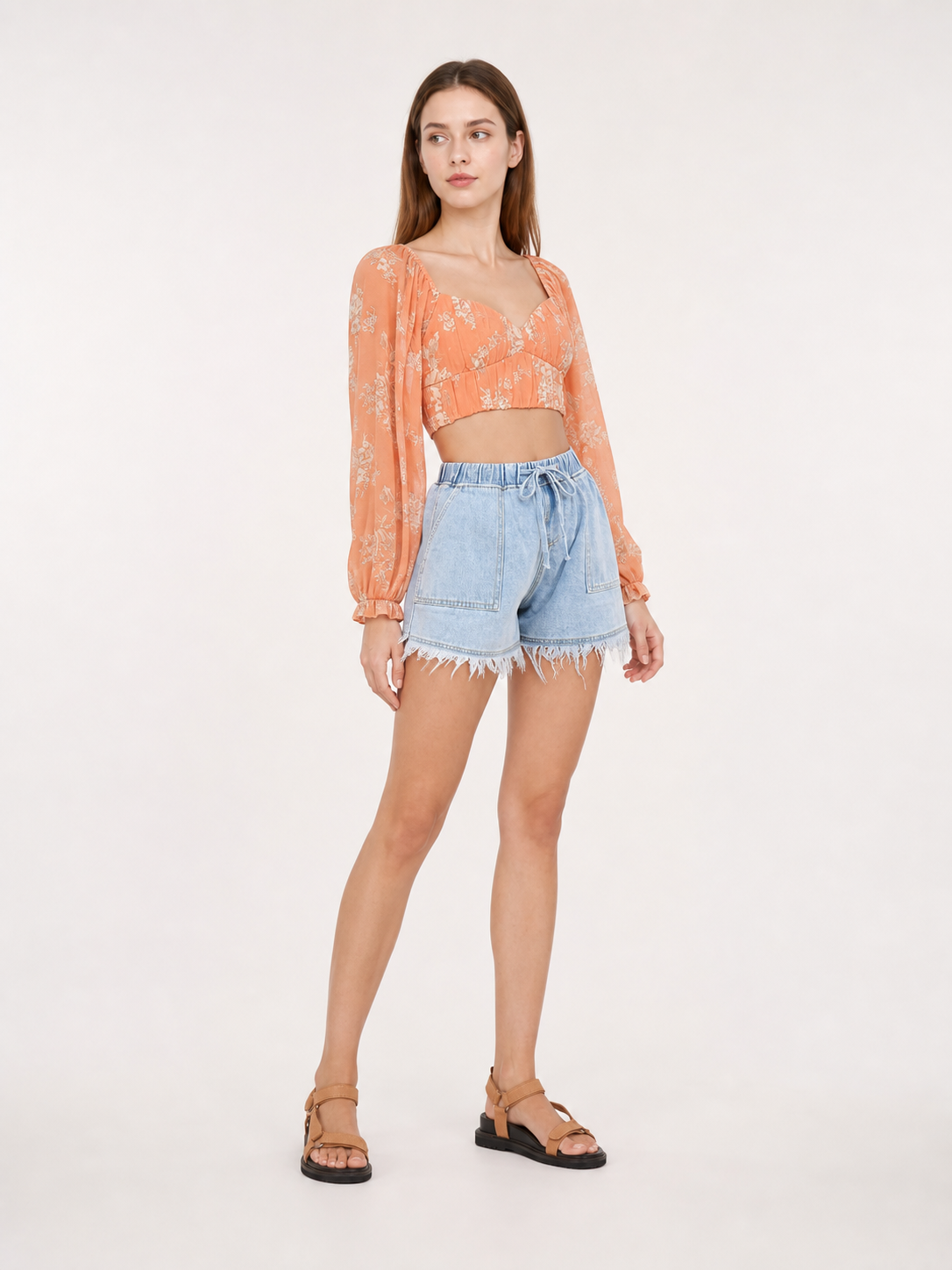 Light blue denim shorts with a drawstring waist, patch pockets and frayed hems shown in a styled indoor scene