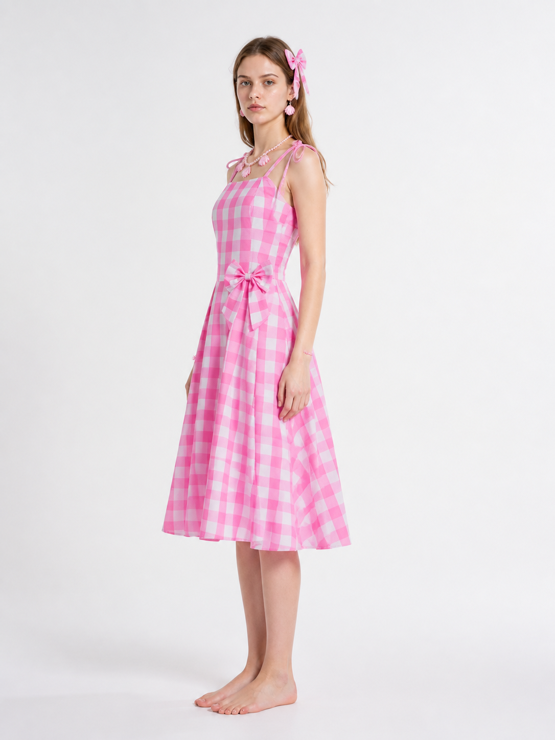 Pink-and-white gingham pinafore dress with a bow side view