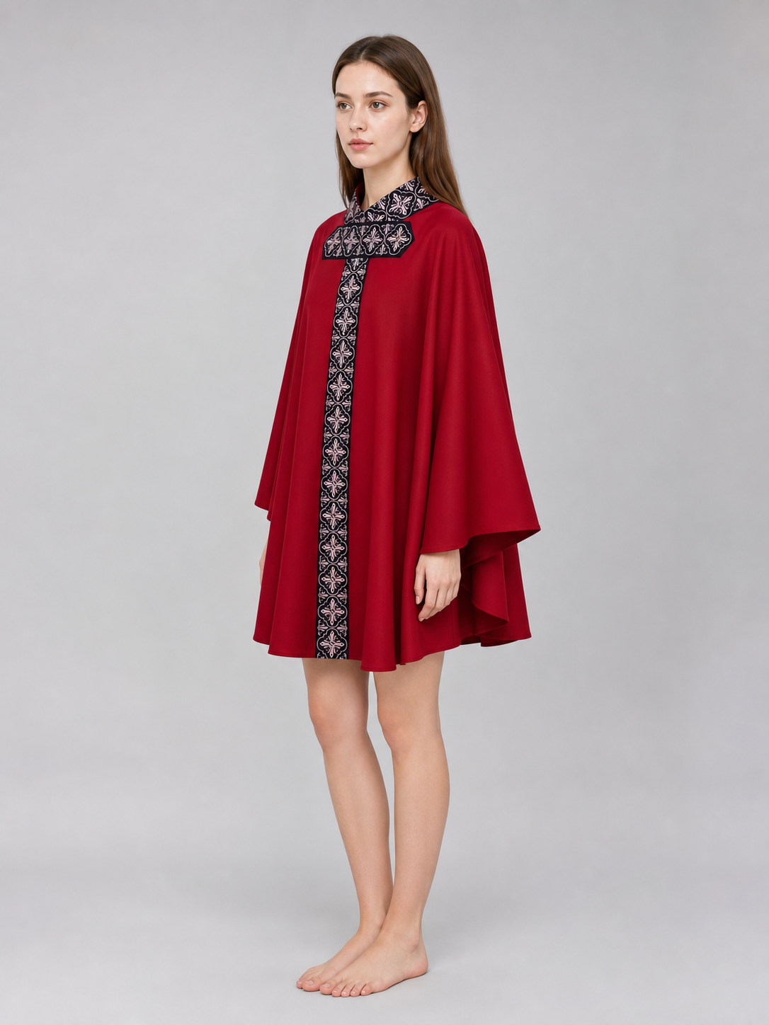 The cape is red with black decorative elements. It has a loose cloak-style silhouette, wide sleeves, and a collar with black patterned detailing. The front features a vertical decorative stripe down the center and a horizontal stripe across