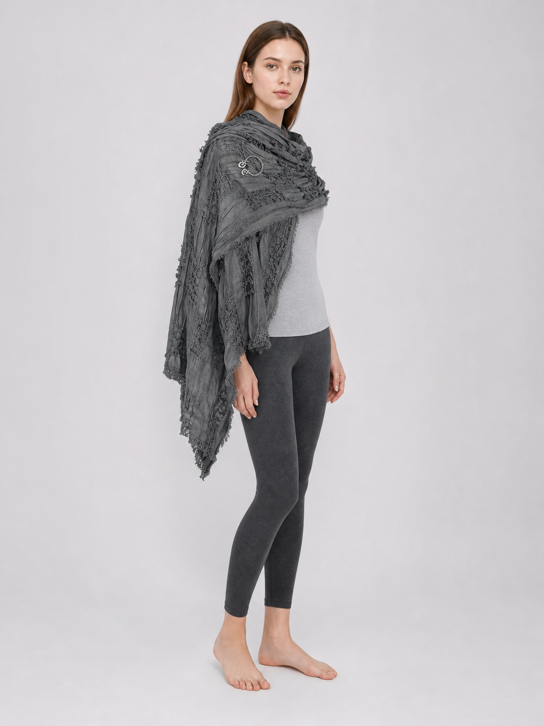 This large scarf-wrap is designed as a rectangular drape with a striking textured surface. The black-and-gray color palette is accented with lighter gray tones, giving the piece a distinctive look that pairs easily with different outfits. T