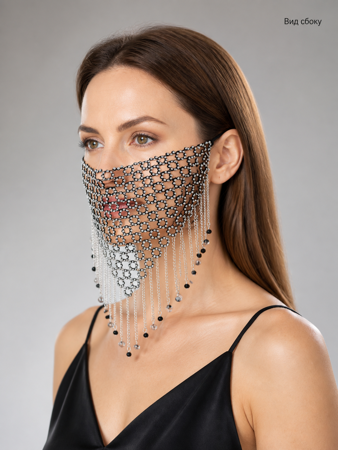 Side view of a black and silver chain mesh mask on a model, showing its layered chains and pointed lower edge