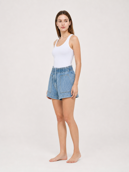 Light blue denim shorts shown in side view on a model, with a loose silhouette, elastic waistband, and front pocket