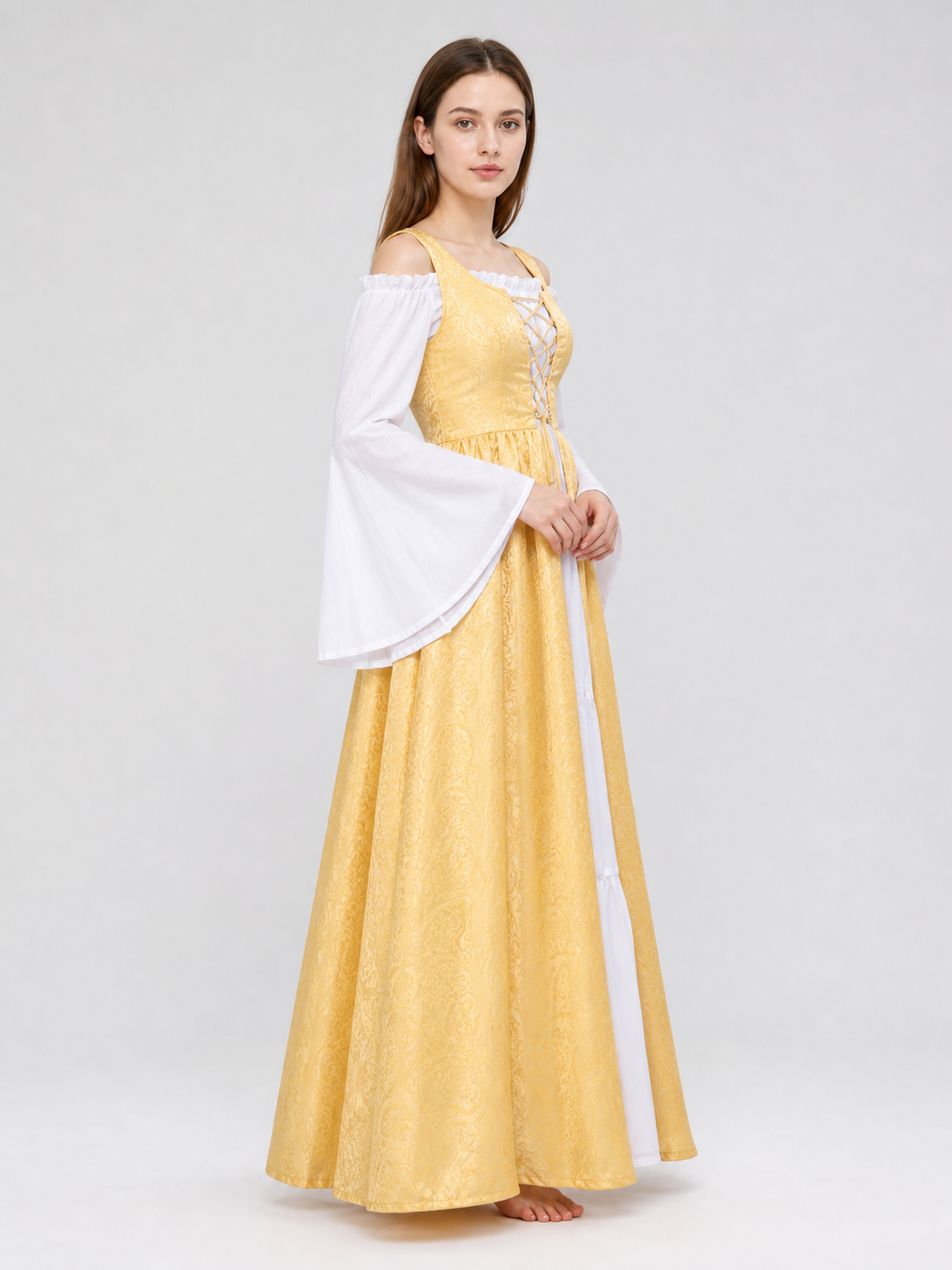 The yellow dress is designed in a fairytale costume style with expressive details inspired by medieval and Renaissance looks. It features a long, floor-length silhouette and a flared skirt paired with a fitted waistline. The front of the bo