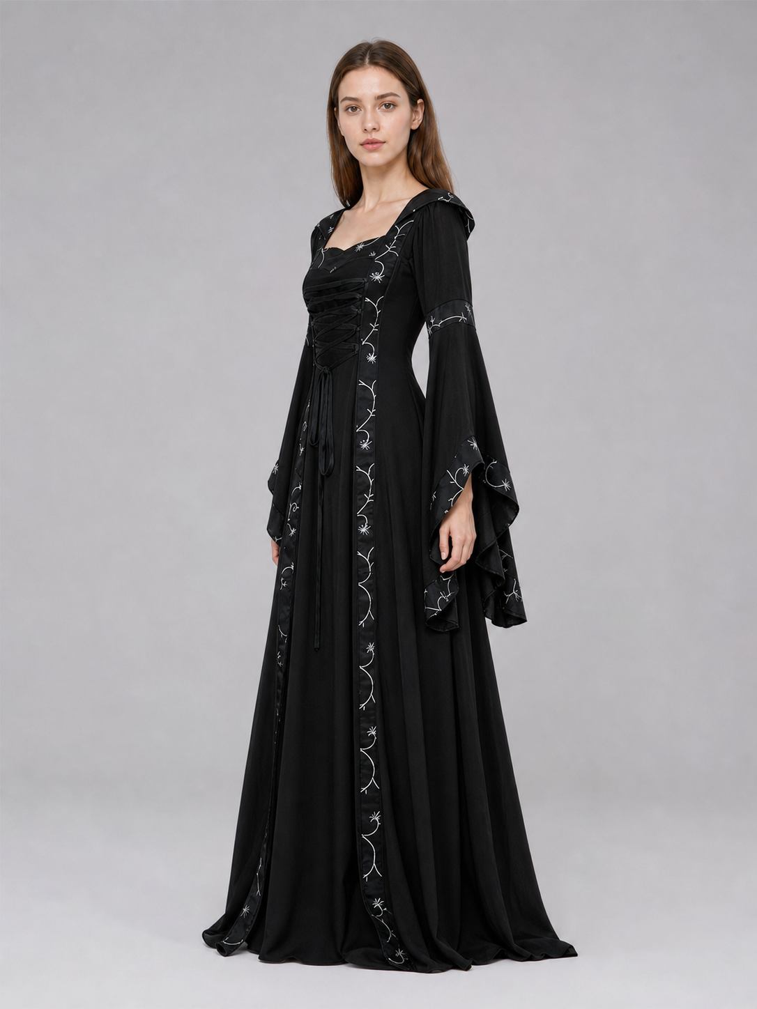 The dress is designed in a gothic style with elements of Victorian aesthetics. The model features a flared silhouette, a square neckline, and long sleeves with flared cuffs. The bodice is decorated with gathers that emphasize the garment’s 