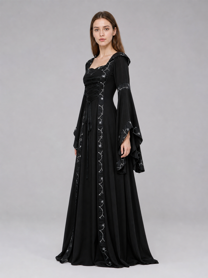 The dress is designed in a gothic style with elements of Victorian aesthetics. The model features a flared silhouette, a square neckline, and long sleeves with flared cuffs. The bodice is decorated with gathers that emphasize the garment’s 