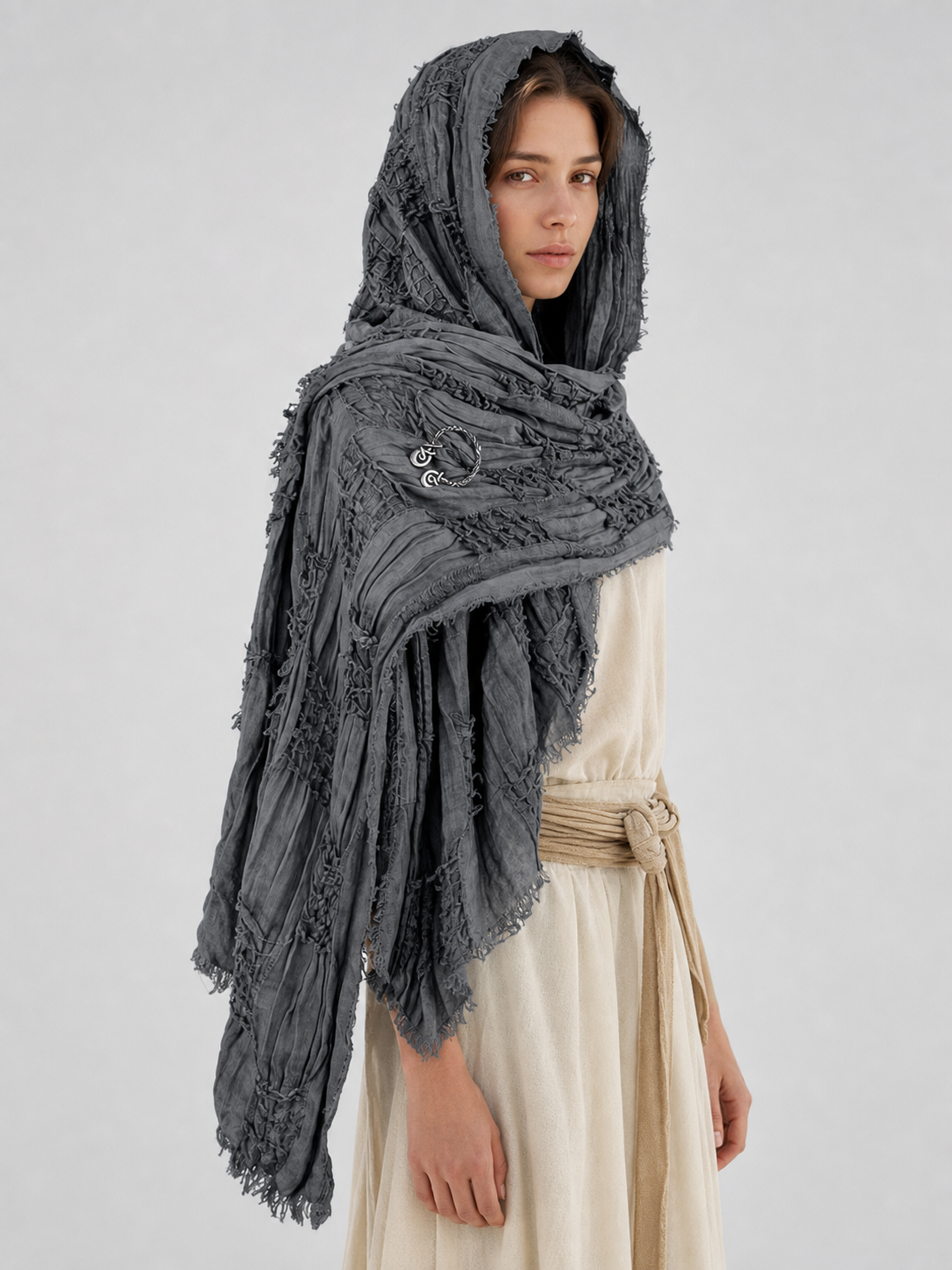 This large scarf-wrap is designed as a rectangular drape with a striking textured surface. The black-and-gray color palette is accented with lighter gray tones, giving the piece a distinctive look that pairs easily with different outfits. T