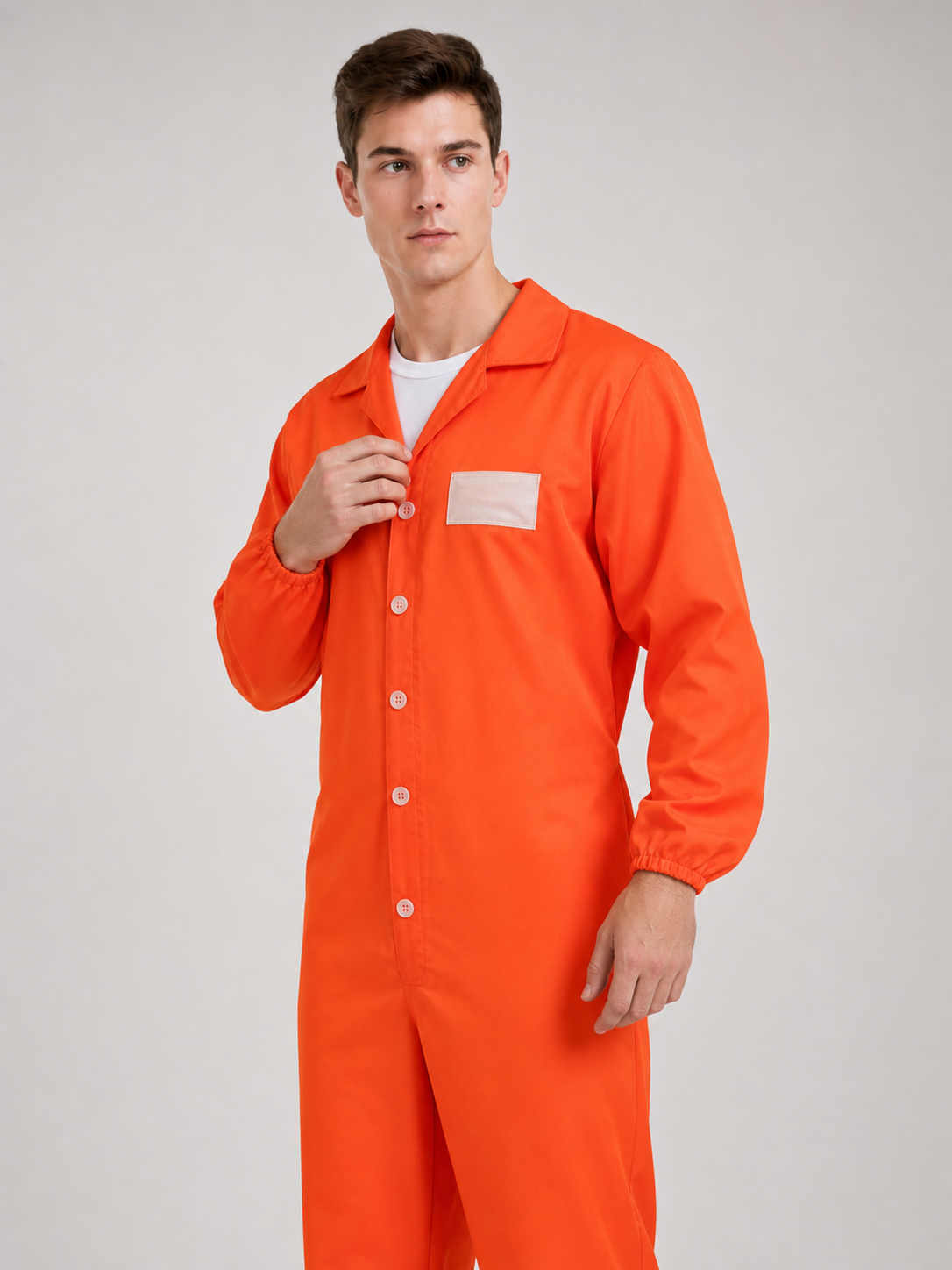 Orange coverall with a smooth fabric look, open collar, white buttons, chest patch, and elastic cuffs, shown in a close angled upper-body view