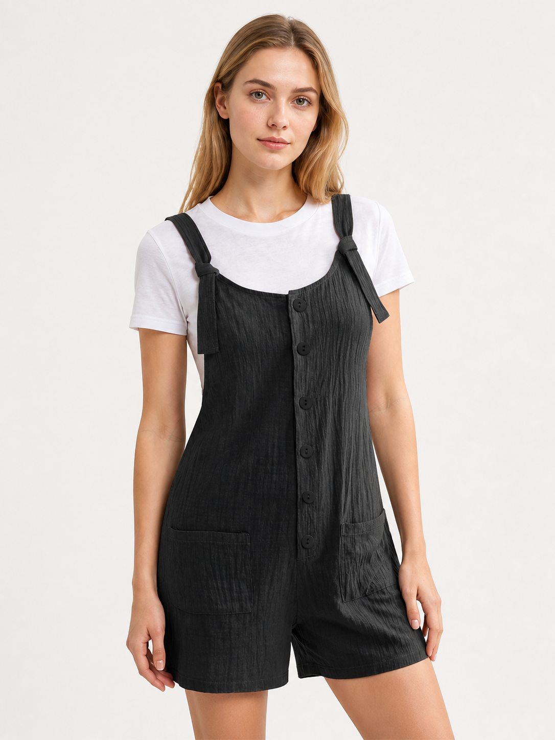Black bib shorts with front buttons, shoulder straps, and pockets, shown full-body on a model wearing a white T-shirt