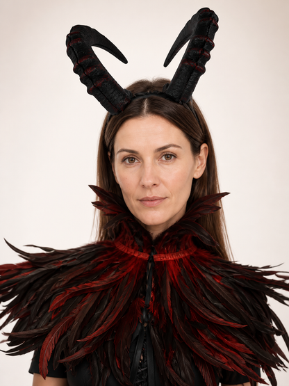 Close front portrait showing the black and red textured horns and the upper edge of the layered feather collar