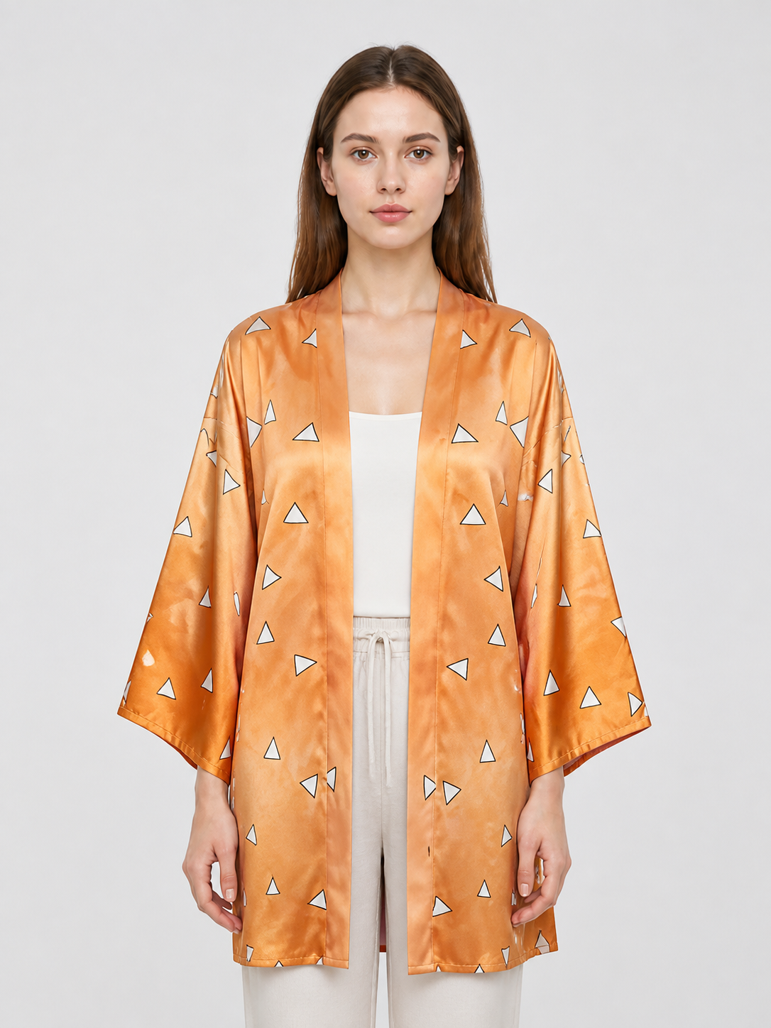 Close-up of the orange patterned robe on a model, showing the open front, wide sleeves, and shiny fabric surface