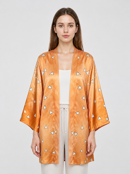 Close-up of the orange patterned robe on a model, showing the open front, wide sleeves, and shiny fabric surface