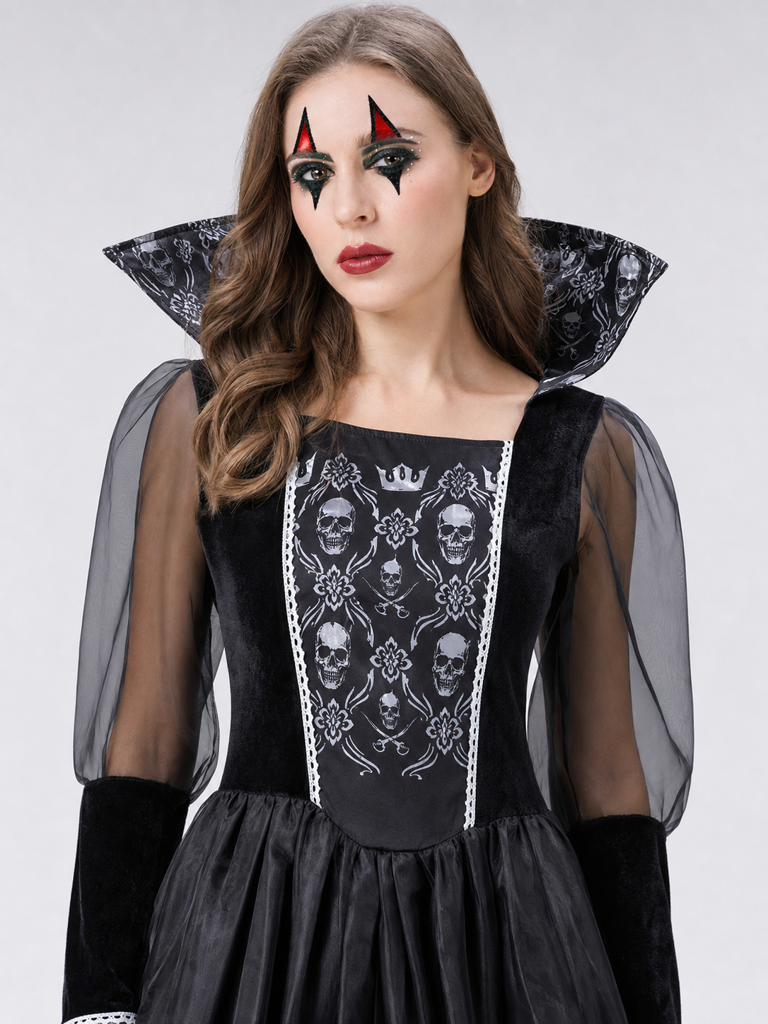 Black gothic-style dress with silver-white decorative skull motifs. The design features a long silhouette with sheer mesh sleeves and an accent neckline with a pointed shape. Silver decorative trim is placed across the chest, complementing 