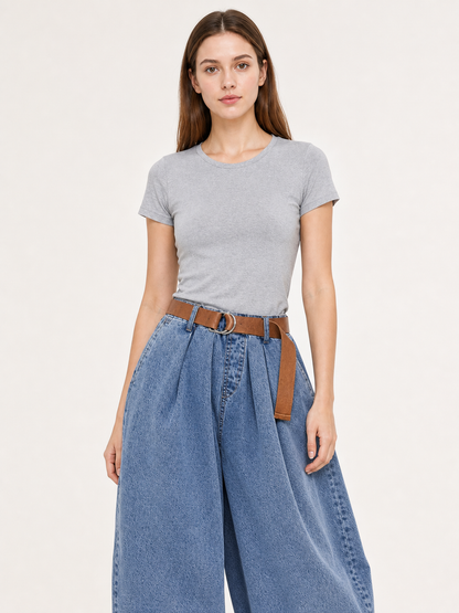 Upper-body view of a model wearing blue denim pants with a brown belt, metal ring buckle, pleated front, and side pockets