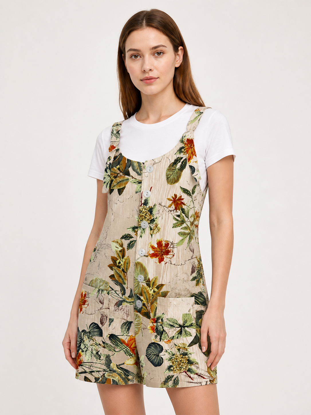 Upper-body view of a model wearing a beige floral romper over a white T-shirt, showing the rounded neckline and straps