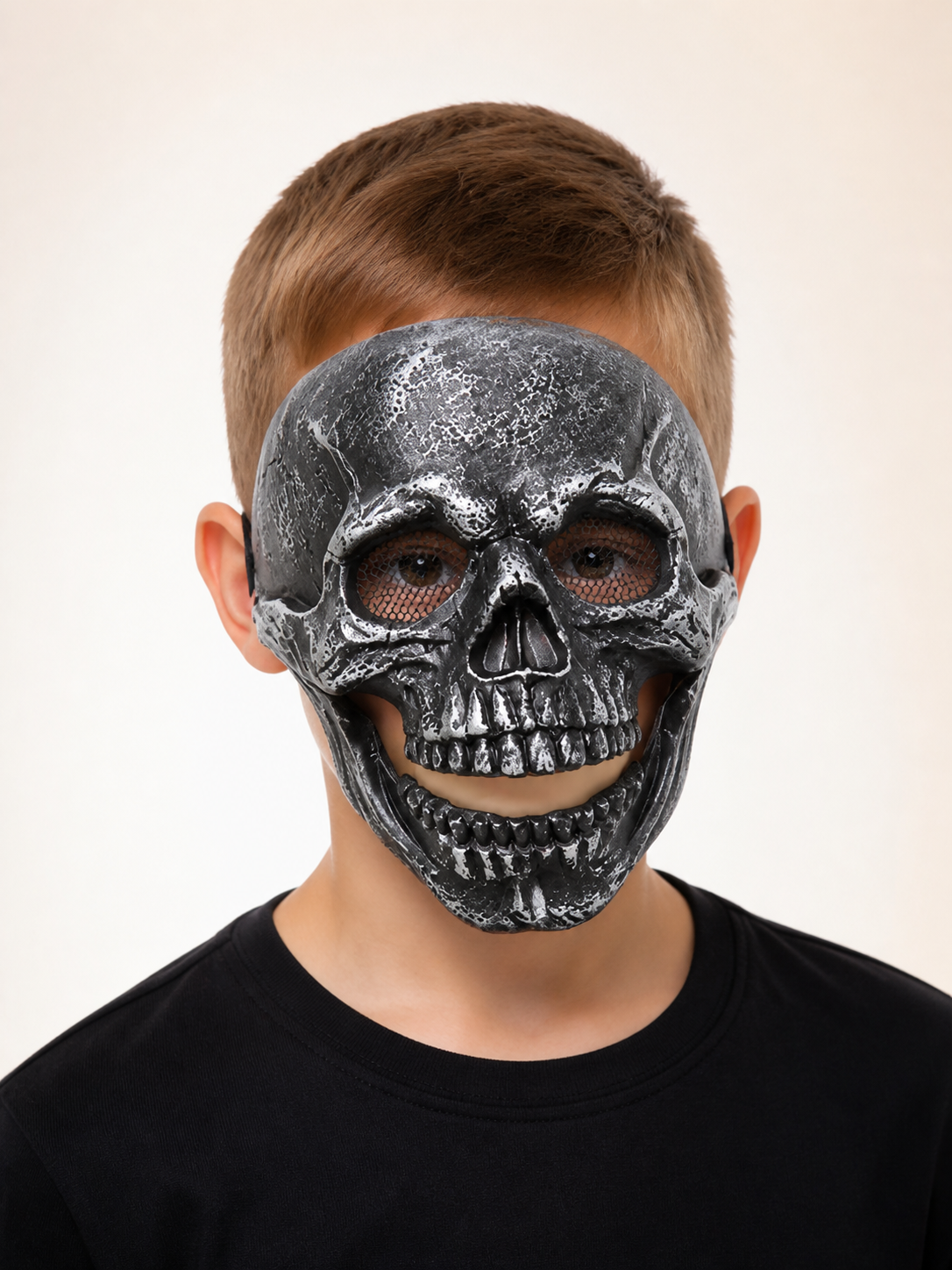 Black skull face mask with hollow eye openings, nose cavity and molded teeth, shown in a close-up front view on a model