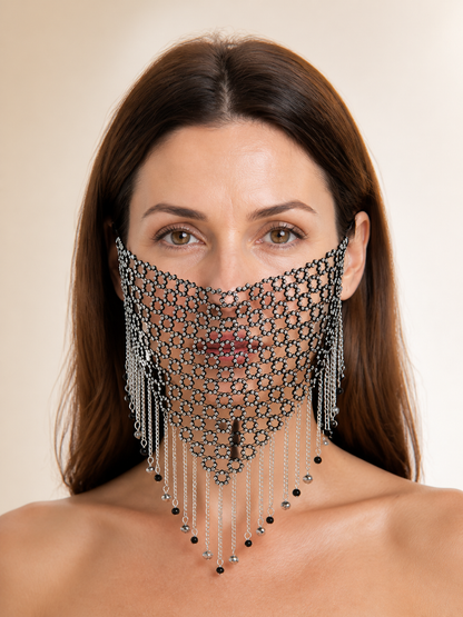 Front close-up of the black and silver chain mesh mask, highlighting its linked pattern, pointed shape, and dangling bead chains