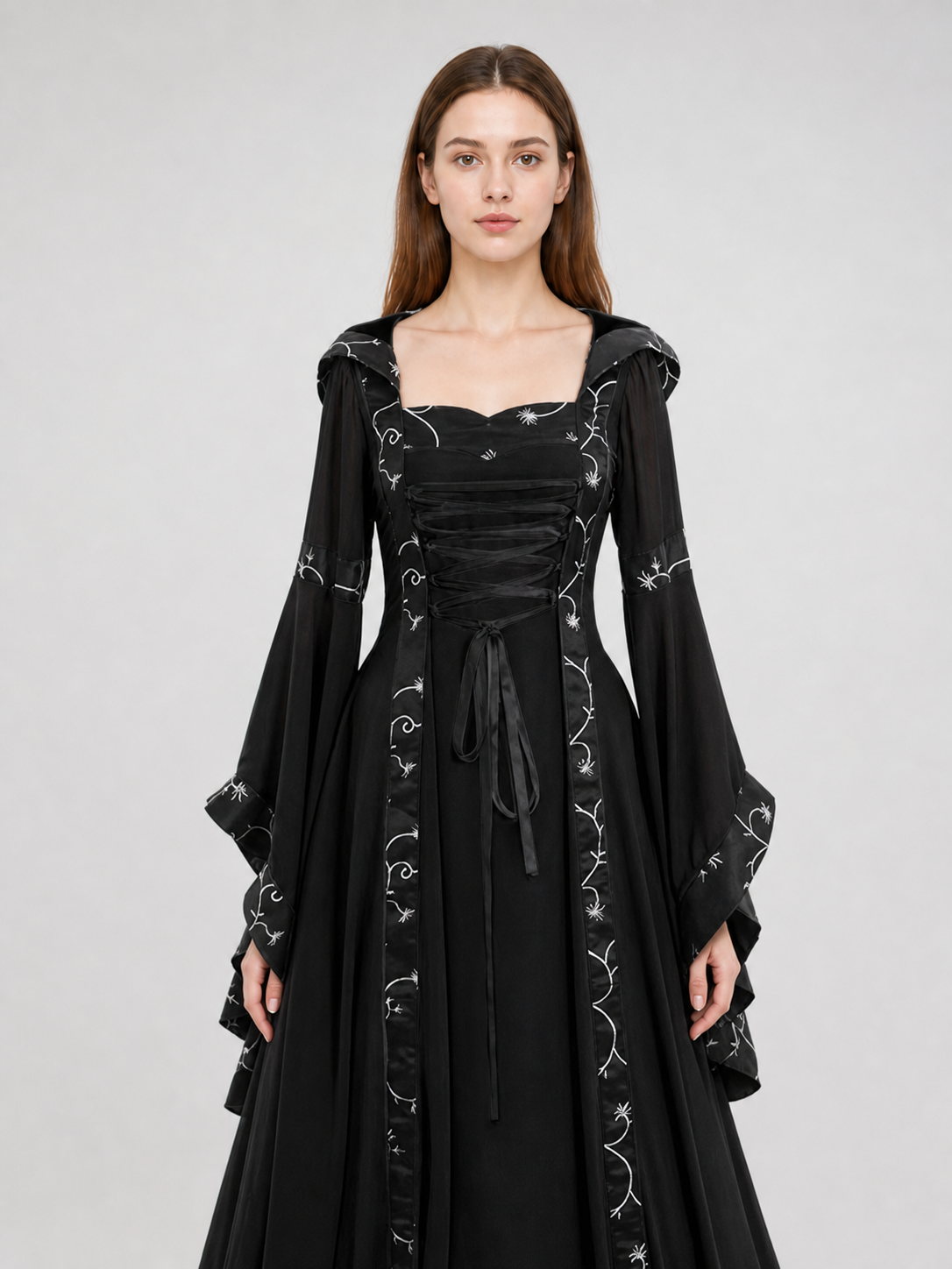 The dress is designed in a gothic style with elements of Victorian aesthetics. The model features a flared silhouette, a square neckline, and long sleeves with flared cuffs. The bodice is decorated with gathers that emphasize the garment’s 