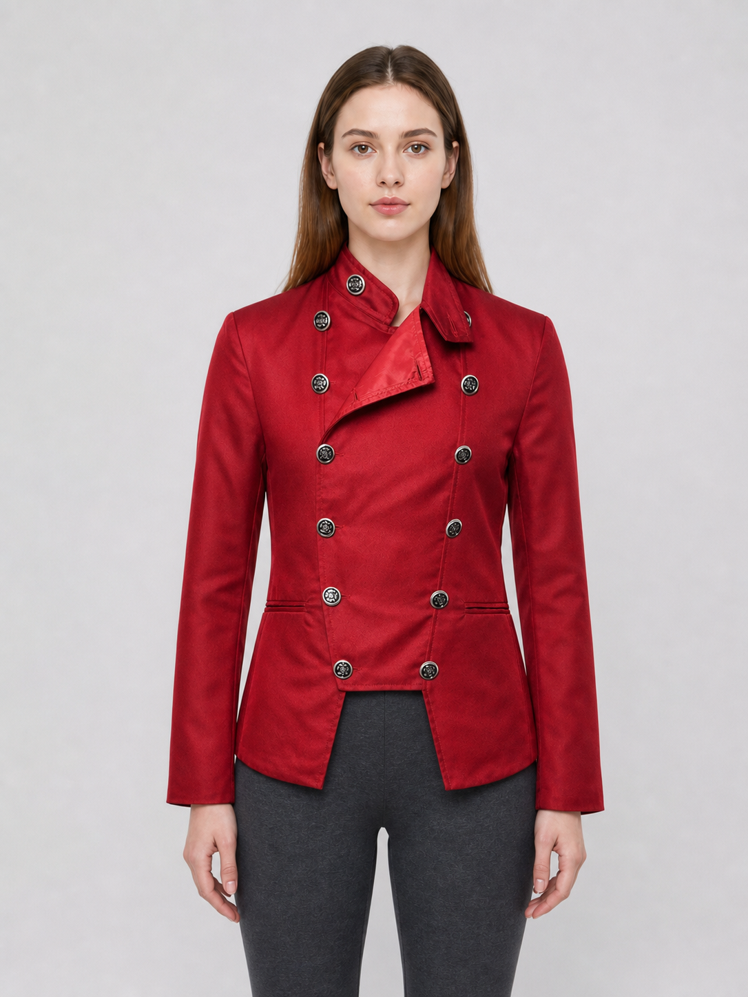 The jacket is presented in a vintage red color and designed in a military style with elements of Gothic aesthetics. The model features a distinctive front construction with a diagonal wrap, giving the garment a bold character. A double row 