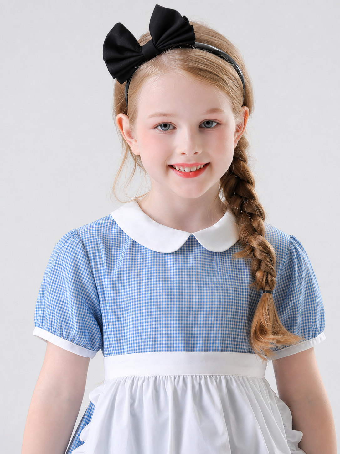 The dress is designed in a retro style, combining a blue-and-white small check pattern with distinctive white details. A white apron-like insert is featured on the front, while the white Peter Pan collar and white waist detail reinforce the