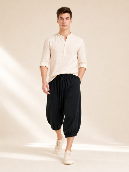 Black cropped pants with a relaxed fit and elastic cuffs, shown on a walking model wearing a light shirt and sneakers