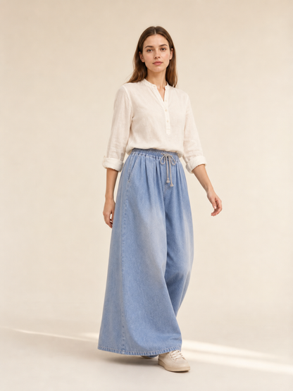 The model features a relaxed style with very wide, full-length legs that create a laid-back silhouette and suit everyday looks. The light blue shade with a subtle denim-like effect makes the piece versatile for warm weather and easy to pair